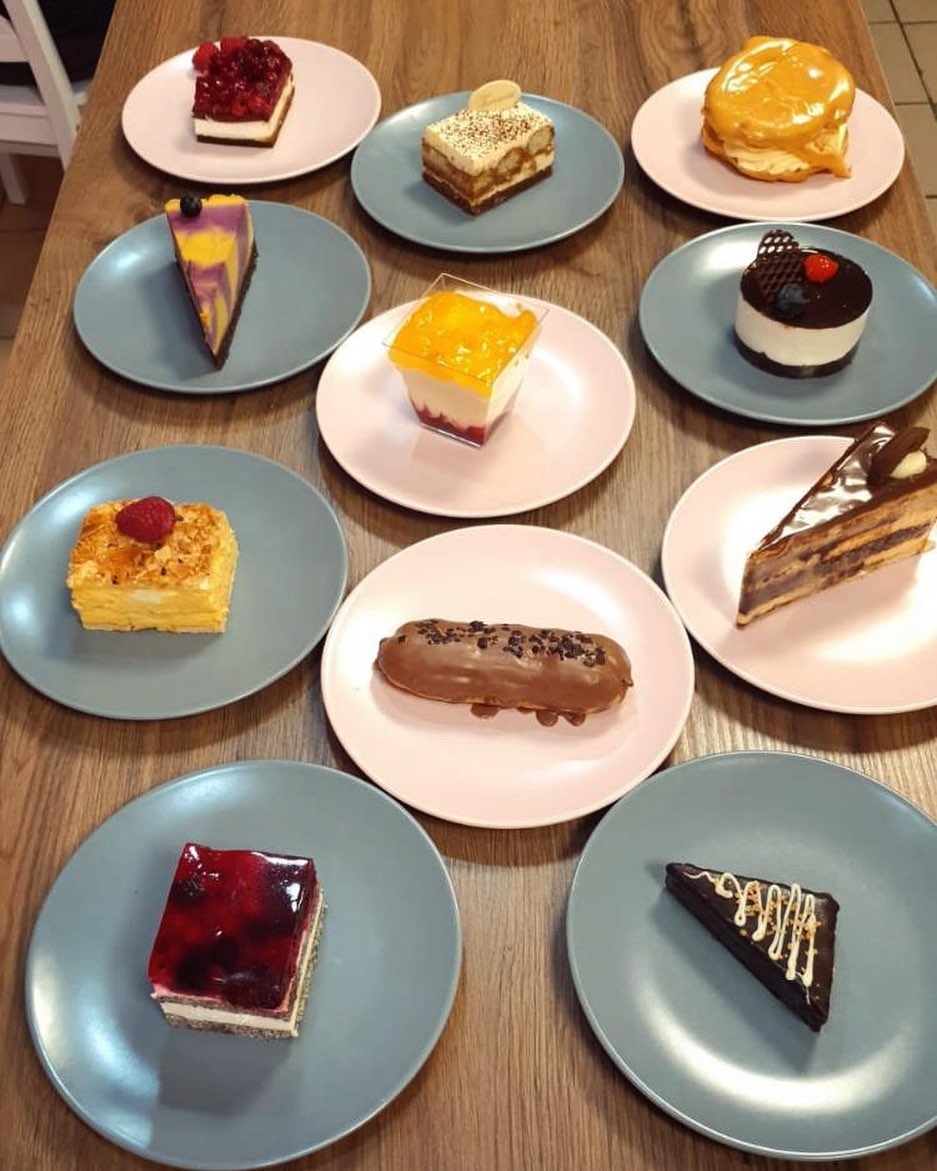 Výber zákuskov a tort na farebných tanieroch